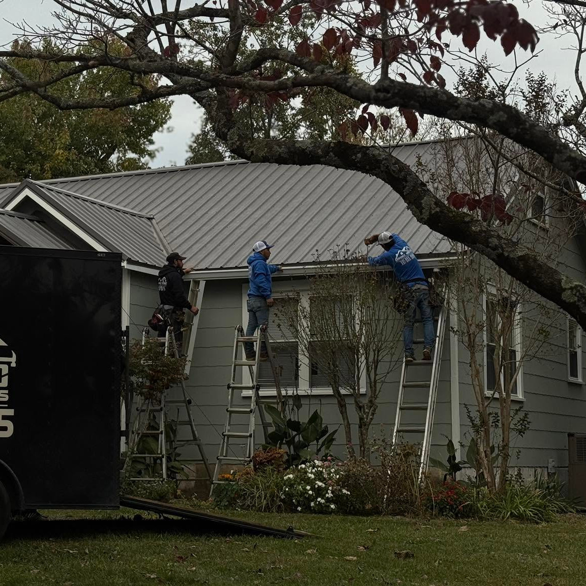 A team of roofers work on a house gutter.