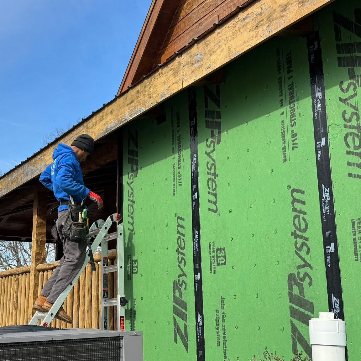 A man prepares to work on a house's siding'.